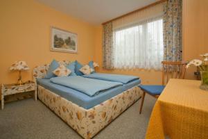 a bedroom with a bed with blue sheets and a window at Haus Fischer in Velden am Wörthersee