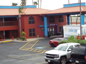 un edificio rojo con coches estacionados en un estacionamiento en Texas Inn Harlingen, en Harlingen