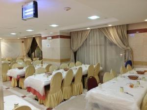 Sala de conferencias con mesas, sillas y TV en Manazel Alaswaf Hotel, en Medina