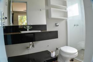 W łazience znajduje się toaleta, umywalka i lustro. w obiekcie Cantinho da Alegria Suítes w mieście Capitólio