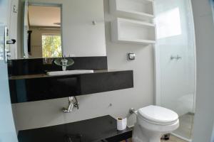 a bathroom with a toilet and a sink and a mirror at Suítes Aconchego in Capitólio