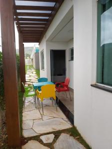 eine Terrasse mit bunten Stühlen, einem Tisch und einem Fenster in der Unterkunft Cantinho da Alegria Suítes in Capitólio
