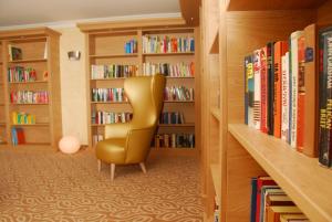 a library with a yellow chair in front of book shelves at Schreiner's - Das Waldviertel Haus in Laimbach am Ostrong