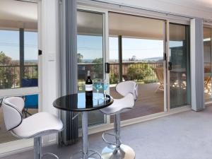 a glass table with a bottle of wine on a balcony at Dromana Bay Views Dromana in Dromana
