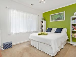 a bedroom with a white bed and a green wall at Karinya Mornington in Mornington