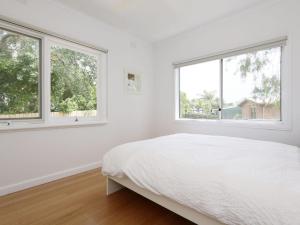 a white bedroom with two windows and a bed at DROMANA BEACH SHACK in Dromana