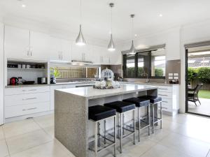 a kitchen with white cabinets and a large island with bar stools at La Dolce Vita Retreat Rye in Rye