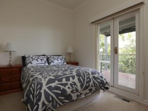 a bedroom with a black and white bed and a window at Bay Views On Browne in Dromana