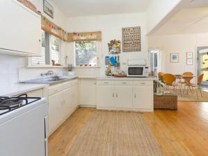 a kitchen with white cabinets and a table and chairs at Home Sweet Home Mount Martha in Mount Martha +4 photos