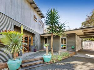 a house with palm trees in pots in front of it at Point Leo Beach House Point Leo in Mount Martha