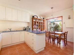 a kitchen with white cabinets and a table and chairs at Seaviews Mornington in Mornington