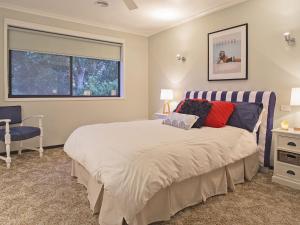 a bedroom with a bed and a chair and a window at Roanjoka Dromana in Dromana
