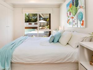 een slaapkamer met een groot wit bed met blauwe kussens bij WAIKIKI BLAIRGOWRIE in Blairgowrie +12 foto's