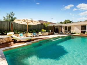 een zwembad met stoelen en een parasol in de tuin bij WAIKIKI BLAIRGOWRIE in Blairgowrie