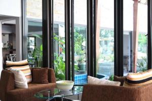 a living room with chairs and a table and windows at Huay Kaew Palace 1 in Chiang Mai