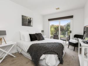 a white bedroom with a bed and a desk at Bangalow Mornington in Mornington