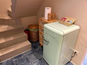 a small white refrigerator in a room with stairs at 三田包棟旅宿MITA Inn in Tainan