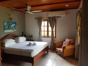 una camera da letto con un letto, una sedia e una finestra di Villa Creole a La Digue