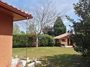 un patio con una casa y un árbol en Landes OCEANES - Chambres privées dans villa avec jardin en Lit-et-Mixe