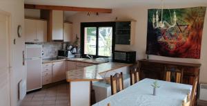 uma cozinha com uma mesa e um frigorífico branco em Landes OCEANES - Chambres privées dans villa avec jardin em Lit-et-Mixe