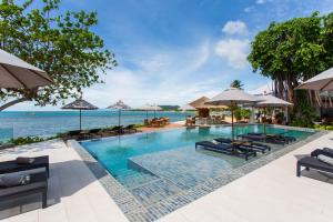 a pool at a resort with chairs and umbrellas at Rocky's Boutique Resort - Veranda Collection Samui in Lamai
