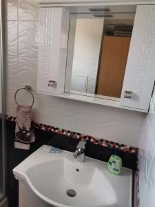 a bathroom with a white sink and a mirror at Апартамент Стил in Velingrad