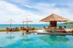 a pool at a resort with tables and umbrellas at Rocky's Boutique Resort - Veranda Collection Samui in Lamai