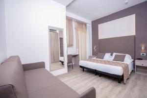 a bedroom with a bed and a couch and a mirror at Hotel Baby in Rimini