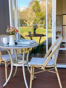 a table and chairs on a porch with a table and flowers at Flower Farm Tamborine Mountain in Mount Tamborine