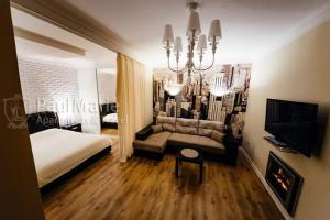 a bedroom with a bed and a couch and a chandelier at PaulMarieApartments on Sovetskaya in Brest