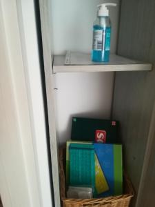 ein Regal mit einer Flasche Desinfektionsmittel und Büchern in der Unterkunft Var Apartman in Miskolc