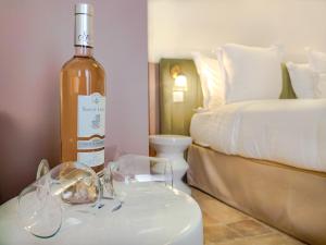 a bottle of wine sitting on a table next to a bed at Aparthotel AMMI Vieux Nice in Nice