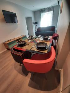 a dining room table with red chairs in a room at 4 Apt T2 50 à 60 M2 déplacement "PRO" ou "couple avec enfants" Les Hauts De Bourg " in Bourg-Saint-Andéol