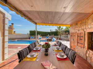 a long wooden table with chairs and a pool at El Descanso in Gata de Gorgos