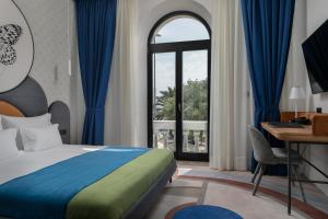 a bedroom with a bed and a desk and a window at Heritage Hotel Porin Makarska in Makarska