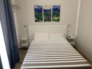 a bed in a bedroom with two paintings on the wall at B&B IV Vico in Miglianico