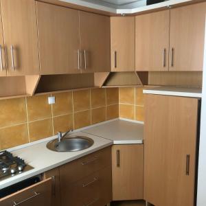 a kitchen with a sink and wooden cabinets at Csorvy Apartman in Hajdúszoboszló