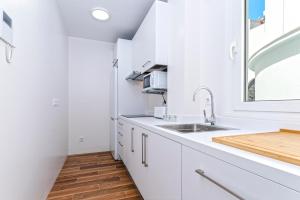 a white kitchen with a sink and a window at Genteel Home San Antonio in Cádiz