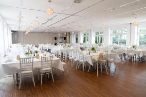 un salón de banquetes con mesas y sillas blancas en Albhotel Fortuna, en Riederich