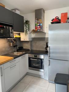 a kitchen with a stainless steel refrigerator and white cabinets at 35m2 neuf, plein sud, dernier etage avec terrasse in Noisy-le-Grand