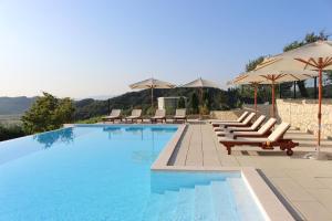 a large swimming pool with lounge chairs and umbrellas at Pension Vuglec Breg in Krapina