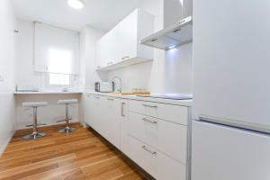a white kitchen with white cabinets and wooden floors at Genteel Home San Antonio in Cádiz +77 photos
