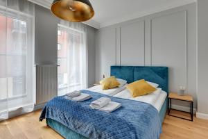 a bedroom with a blue bed with towels on it at Dom & House - Apartments Chmielna Park in Gdańsk