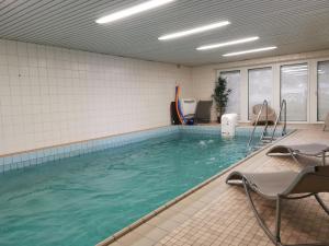 a swimming pool with chairs in a room at Moderne Wohnung mit Privatpool in Büsum