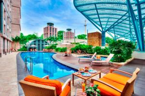 a pool at a hotel with chairs and a table at Resorts World Sentosa - Hotel Michael in Singapore