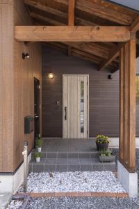 a front door of a house with a wooden patio at Hakuba Kaede House in Hakuba