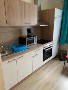 a kitchen with white cabinets and a sink and a microwave at Gasthof zur Post - Standort Am Bahnhof Eiserfeld in Siegen