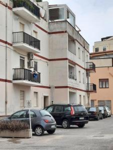 2 voitures garées sur un parking en face d'un immeuble dans l'établissement Il sogno della sirena, à Alghero
