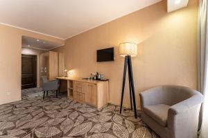 a hotel room with a desk and a chair and a lamp at Renion Park Hotel in Almaty