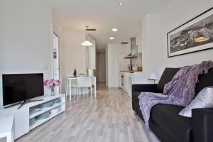 sala de estar con sofá negro y TV en Habitat Apartments Blanca en Barcelona